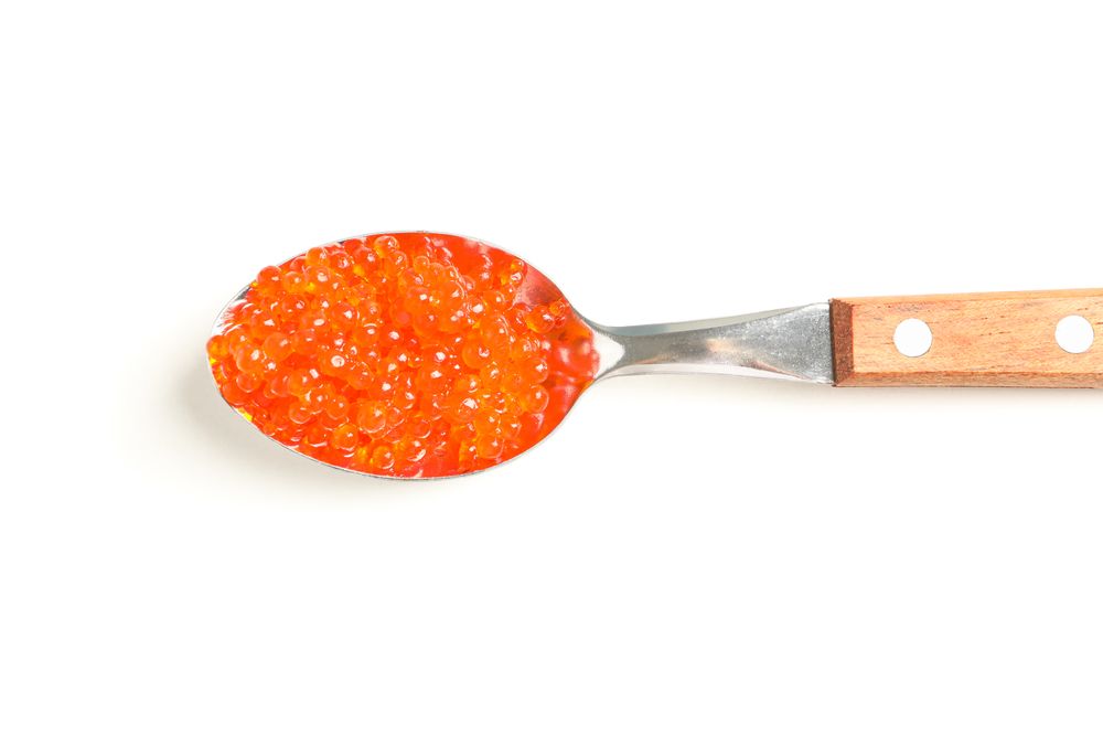 Spoon with red caviar isolated on blank background, top view