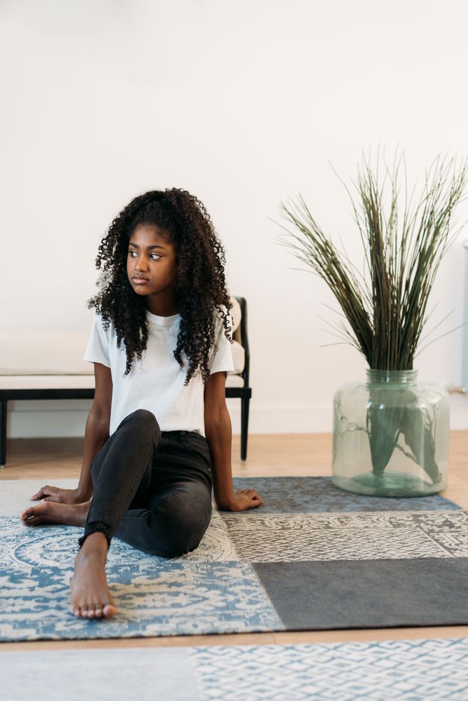 Beautiful young Black teenage girl sitting in a rug