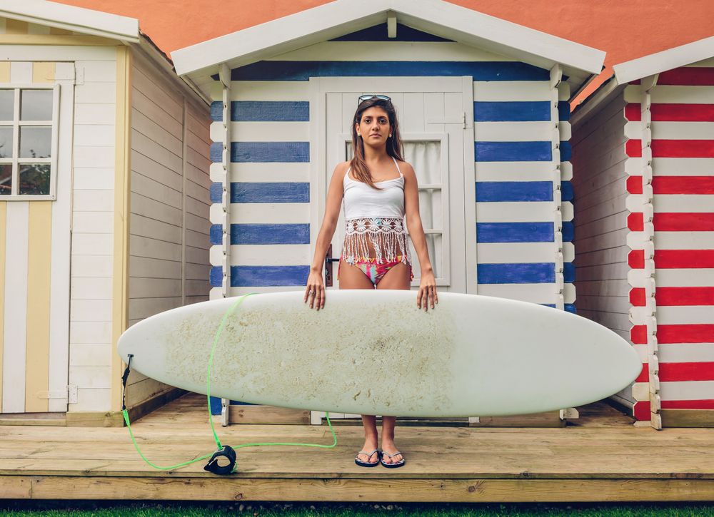 Young surfer woman with top and bikini holding surfboard