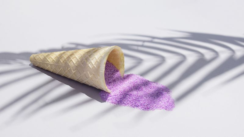 Ice cream cone with purple sand under palm tree shadow