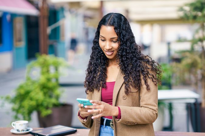 Young Woman Engaging with Smartphone in Outdoor Caf Setting