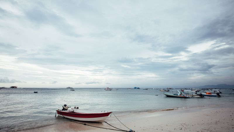 Shot of beautiful beach with small boats moored on the shore in Bali
