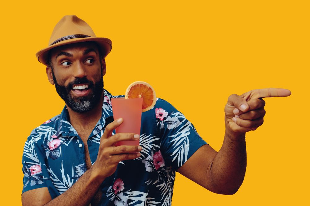 Male giving pointing away while wearing colorful shirt with yellow background