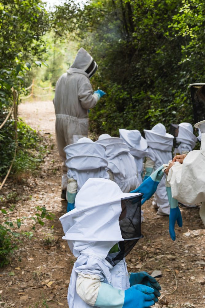 Company of kids in protective costumes in apiary