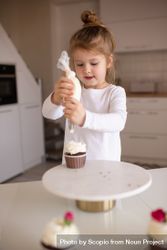 Girl decorating cupcake with whipped cream 5w89W4