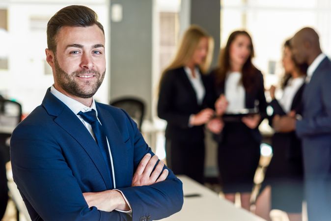 Businessman standing in foreground of busy office