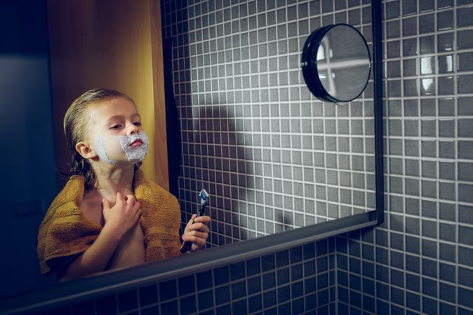 Boy shaving in bathroom with mirror