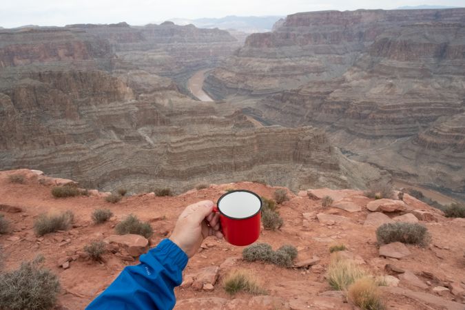 Male with cup of brew at rock