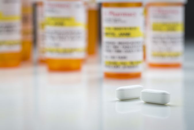 Medicine Bottles and Pills on Reflective Surface With Grey Background