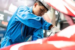 Man working in auto repair shop on red car