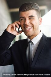 Portrait of smiling man with blue eyes in suit and tie on phone 0PeR25