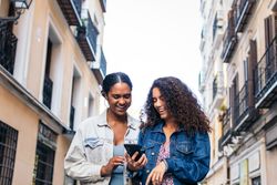 Friends waking in the street using smartphone