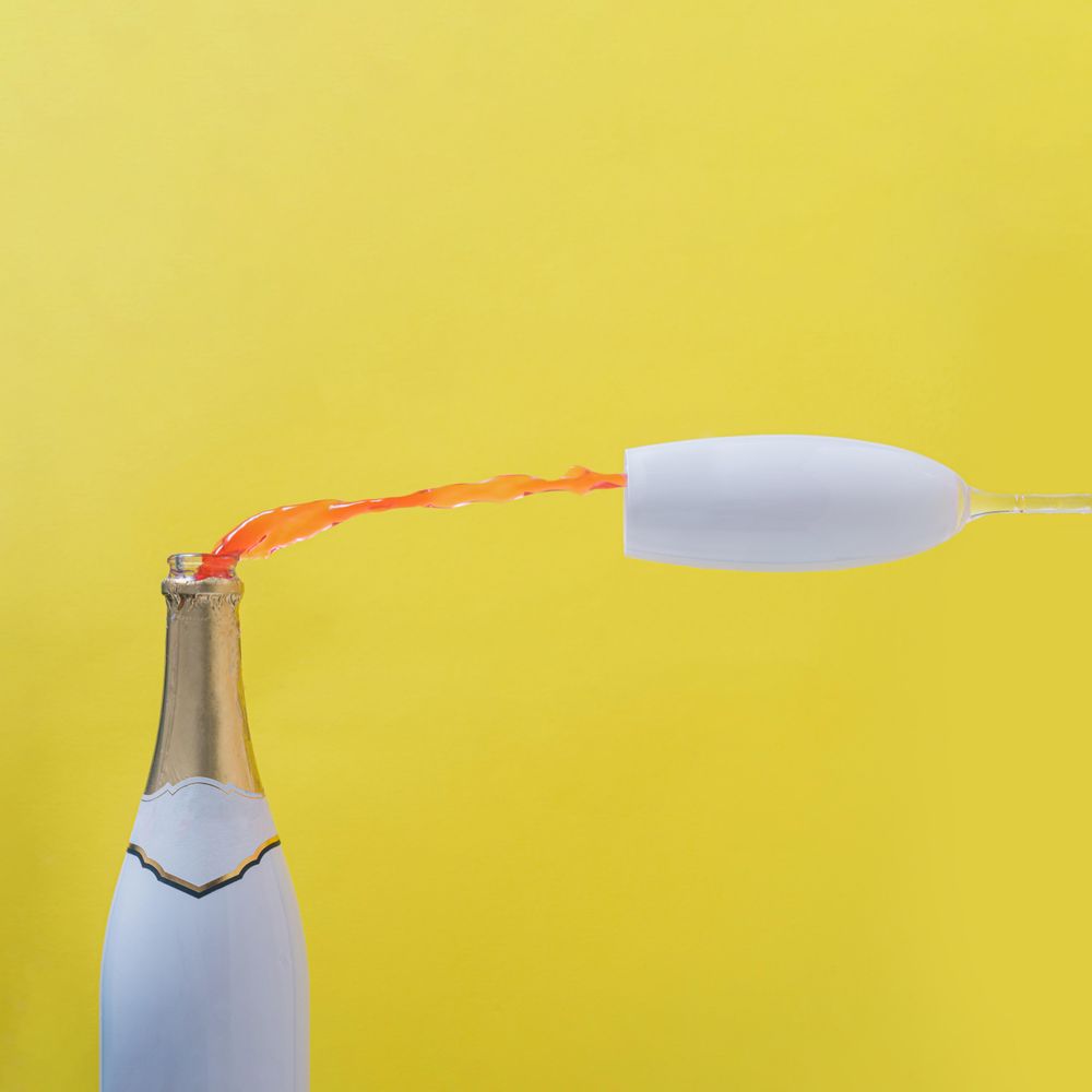 Rose champagne poured into glass against yellow background