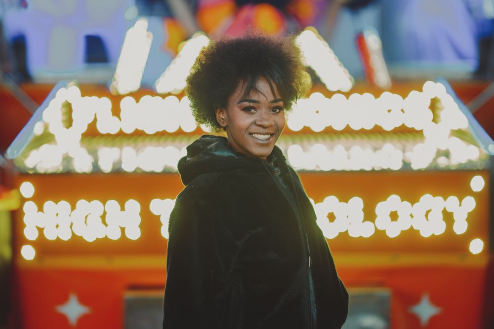 Black female standing near attraction in amusement park