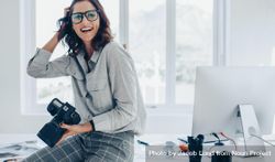 Woman with dslr camera in white office and smiling 5pqLg4