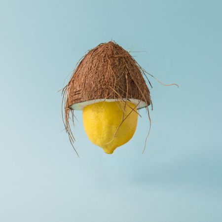 Lemon with with coconut half on pastel blue background