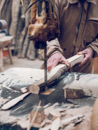 Faceless carpenter cutting wood with scroll saw
