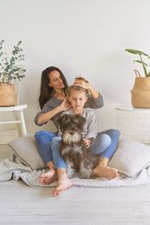 Mother doing hairstyle to son near dog