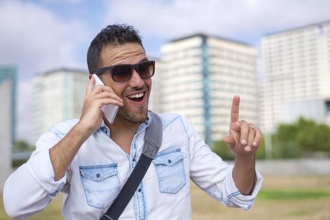 Laughing male having conversation on cell phone with city in background