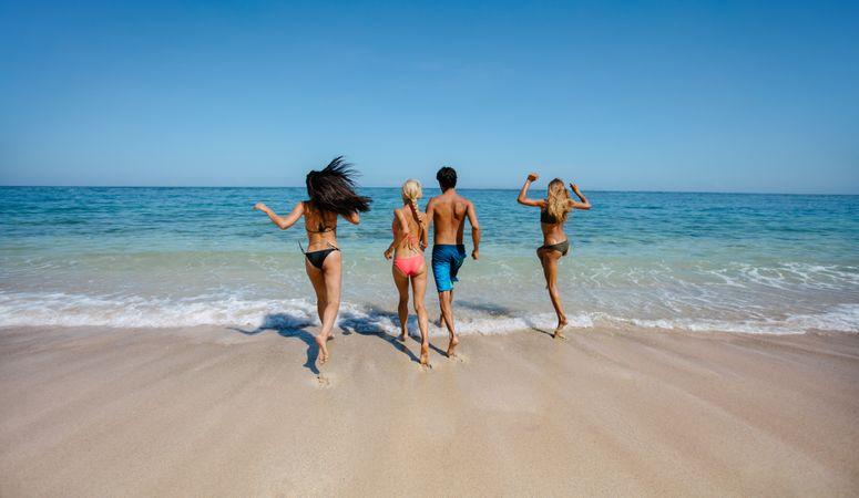 Group of friends running into sea water