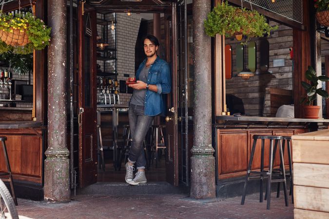 Stylish young man at a cafe entrance door
