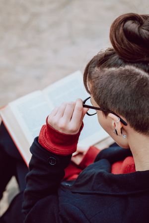 Young woman reading book on bench in park