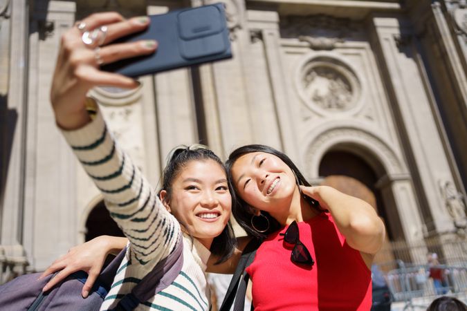Two women taking fun selfie in front of Church in Spain