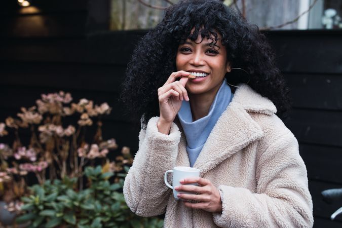 Cheerful Black woman eating cookie