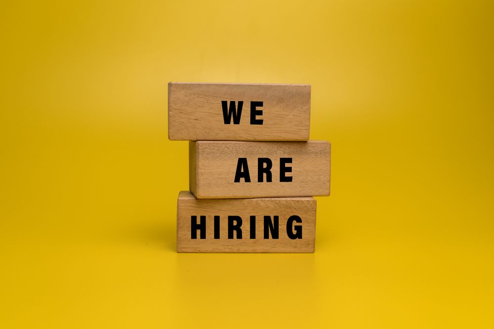 we are hiring words on wooden blocks isolated on yellow background
