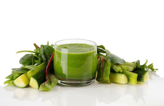 Fresh organic smoothie surrounded by vegetables isolated on background