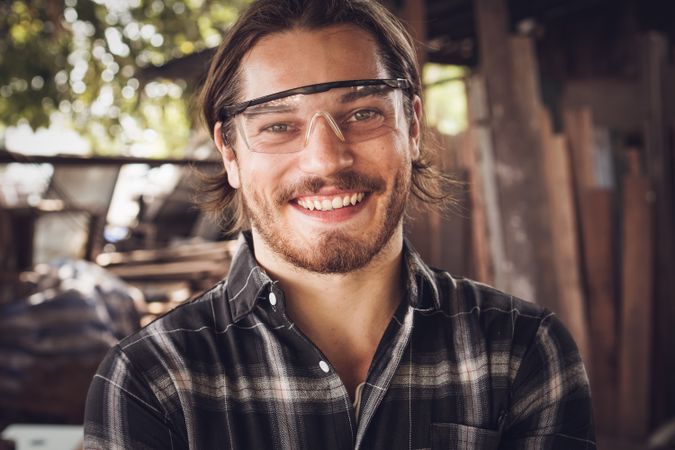 Smiling face of carpenter looking at camera at the workshop