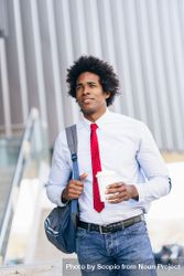 Man wearing tie holding a cup of coffee walking to work 4mK2d0