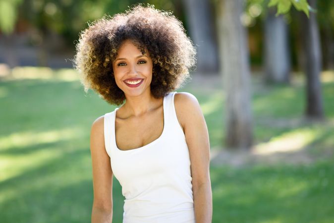 Smiling Black woman with afro hairstyle walking through park