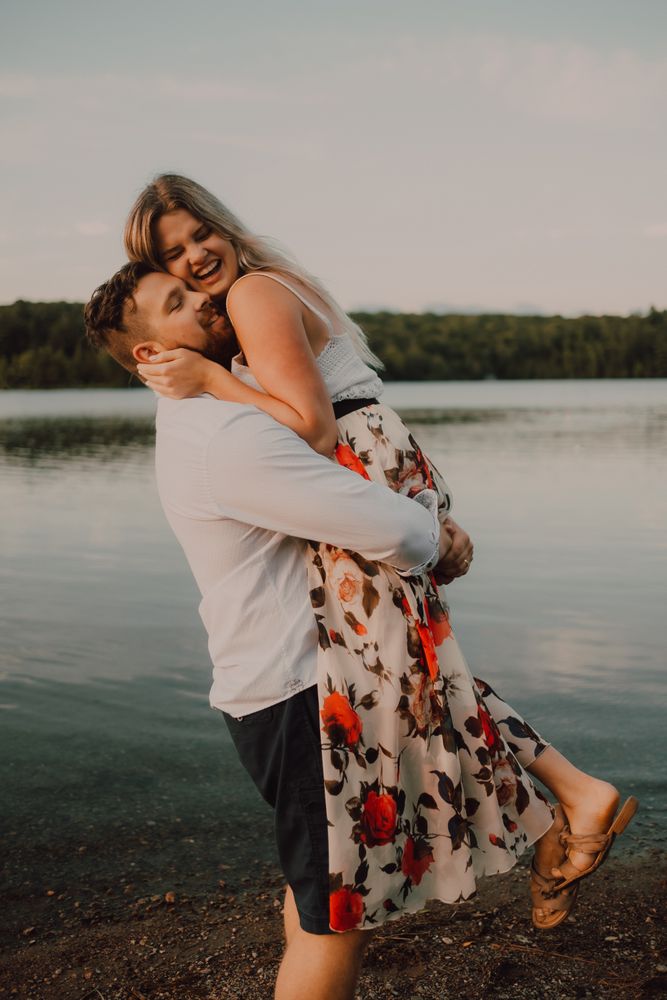Loving man carrying happy woman on hands on shore
