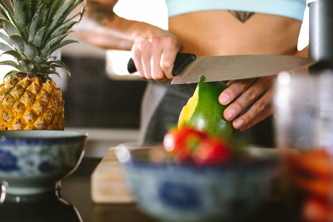 Close up of female hand peeling a fruit with knife at kitchen counter