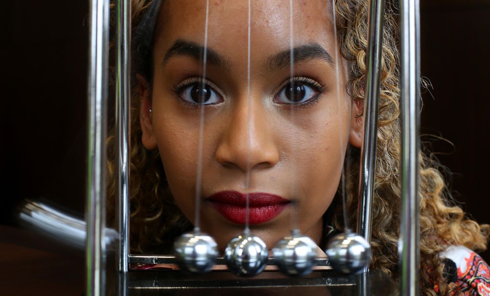 London - UK, April 4, 2016: Young woman with a Newton’s cradle pendulum