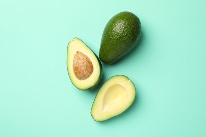 Ripe fresh avocado on mint background, top view