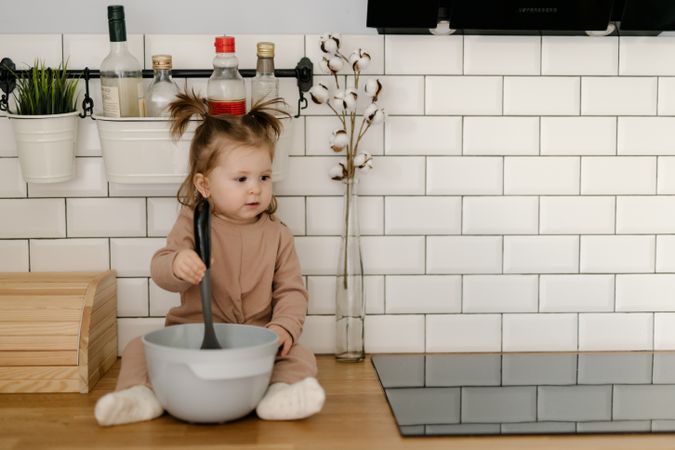 Bay sitting on kitchen counter mixing with spoon