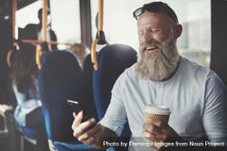 Man with gray beard smiling and video calling while on public transport 56WQz4