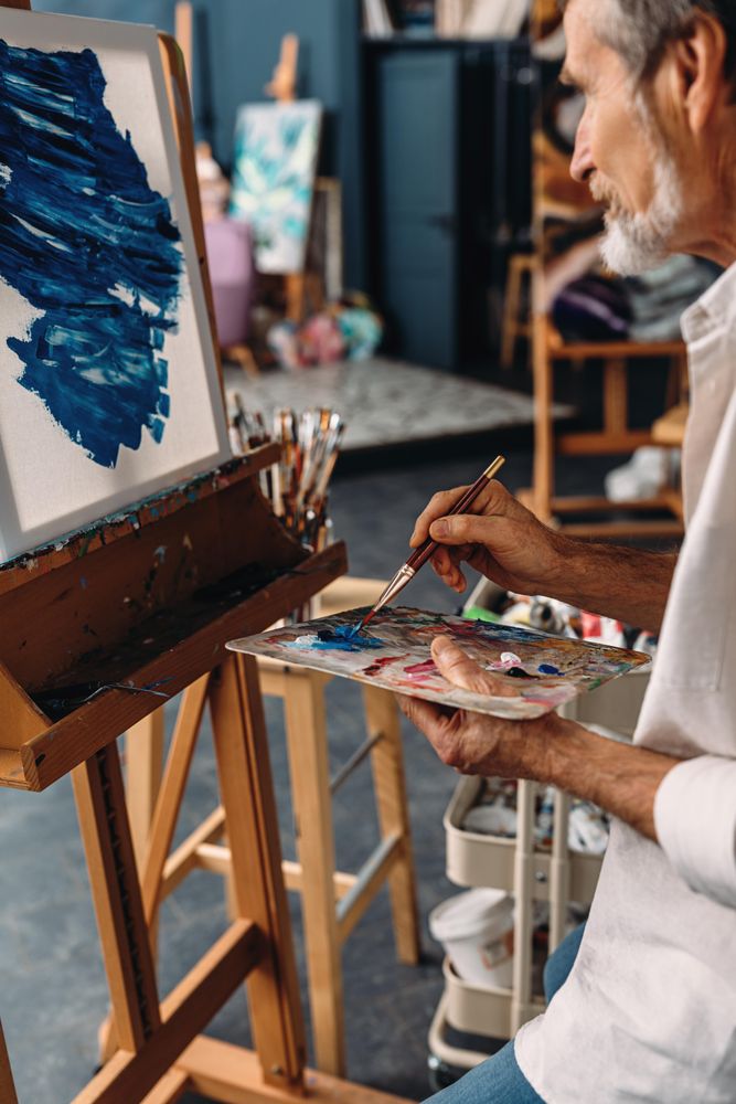 Painter holding a palette and drawing on canvas