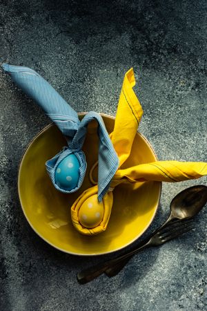 Top view of Easter holiday table setting with decorative blue and yellow eggs on grey table