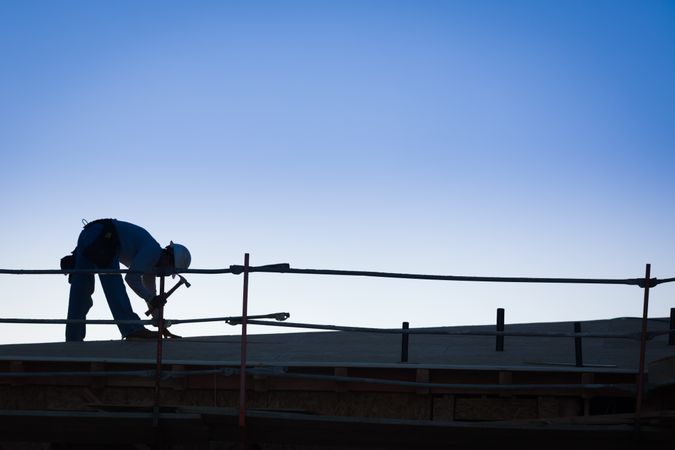 Construction Workers Silhouette on Roof of Building