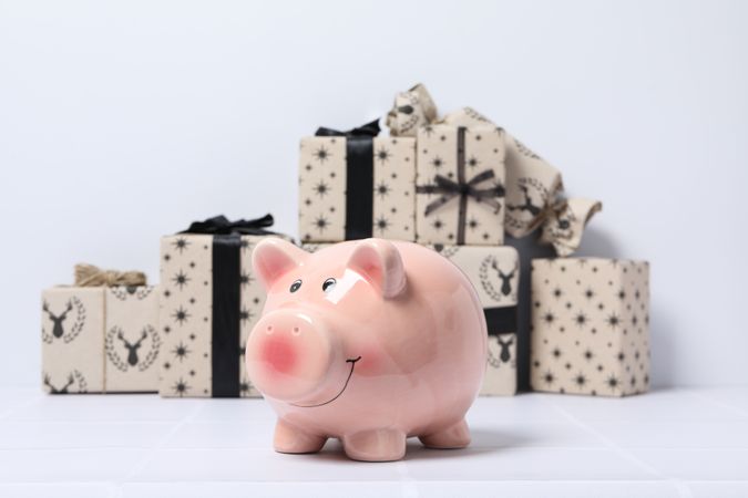 Piggy bank and gift boxes on neutral background