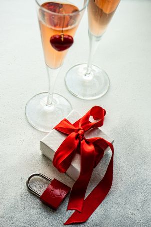 Two glasses of pink champagne with ribbon wrapped gift