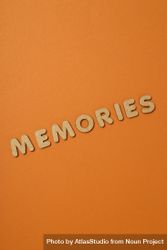 The word “Memories” written in cork in center of dusty orange background, vertical with copy space 0g1984