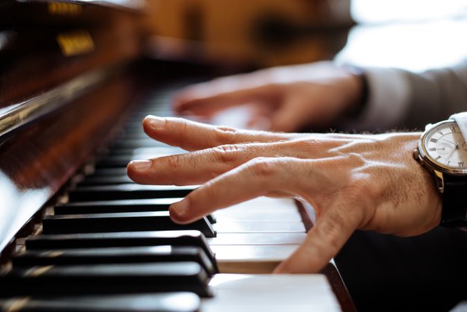 Crop male hands playing piano