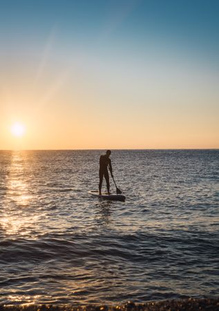 Man practicing paddle surfing with neoprene in a sunrise