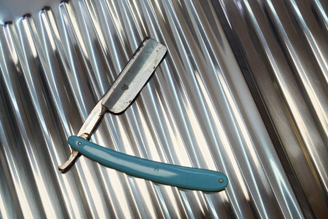 Vintage dangerous razor for haircuts on metal background