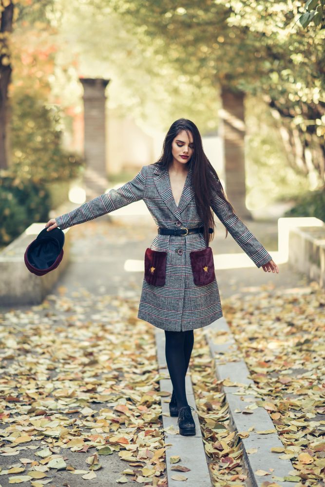 Female in warm winter clothes balancing on park curb