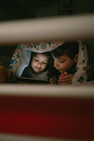 Siblings looking at the tablet in the dark